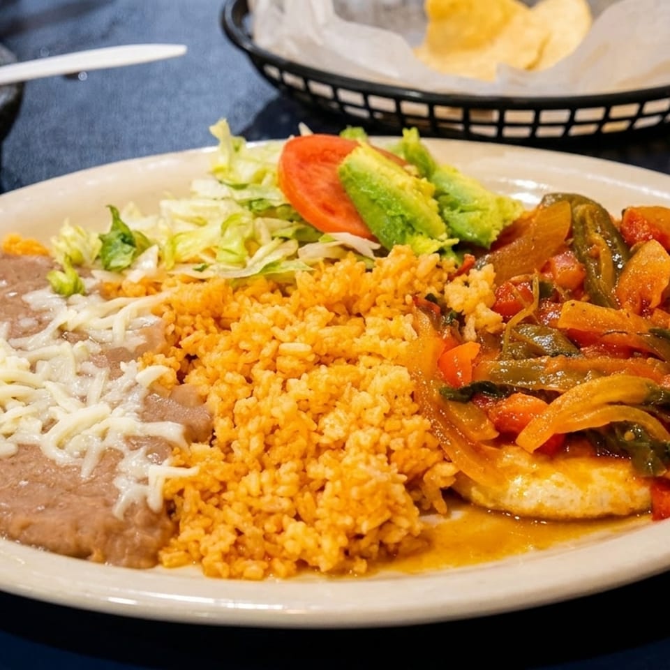 A Mexican dish with refried beans, rice, salad, and a stew of vegetables and chicken.